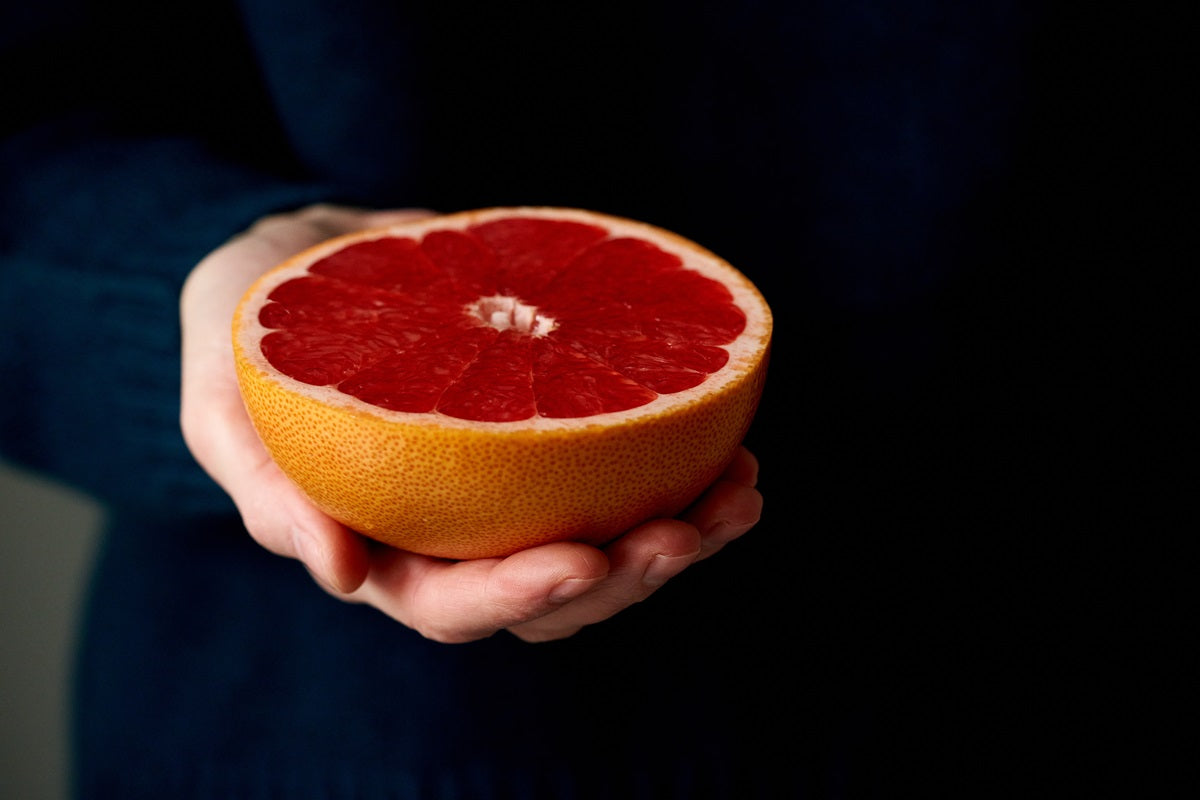 A person holding a grapefruit half