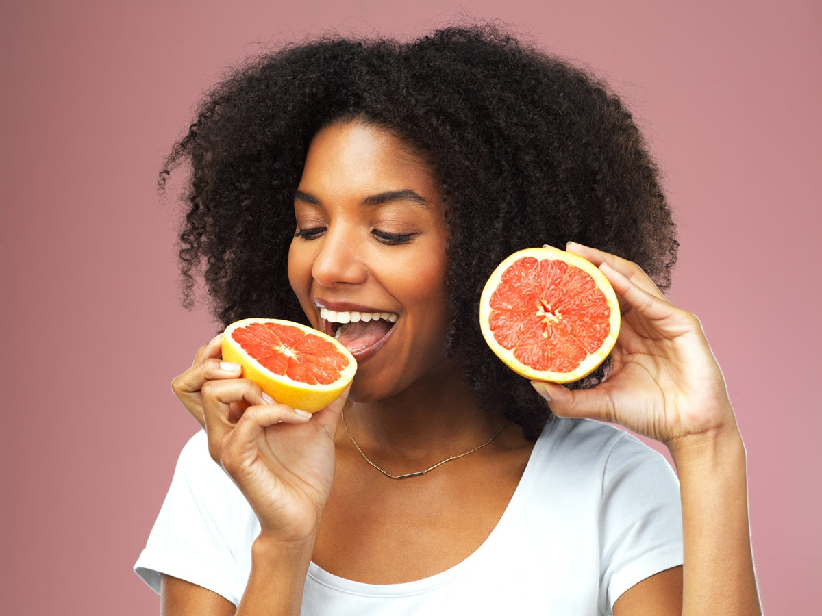 A happy woman eating a grapefruit