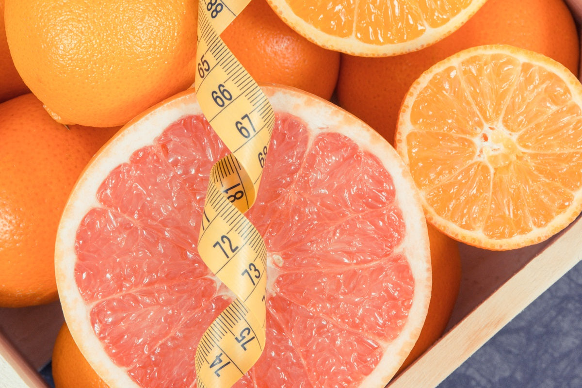 A grapefruit with a measuring tape in front of it
