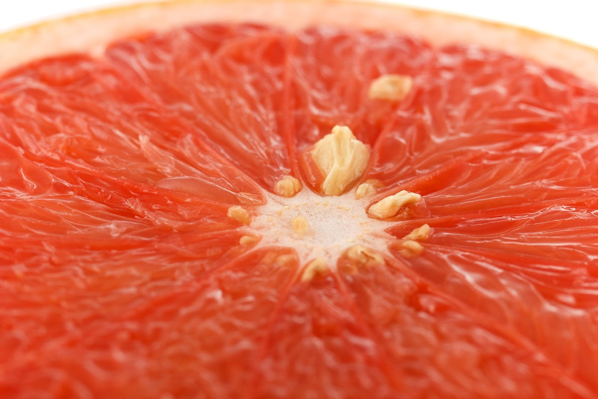 A close up of a grapefruit that is cut in half to show the segments and seeds.