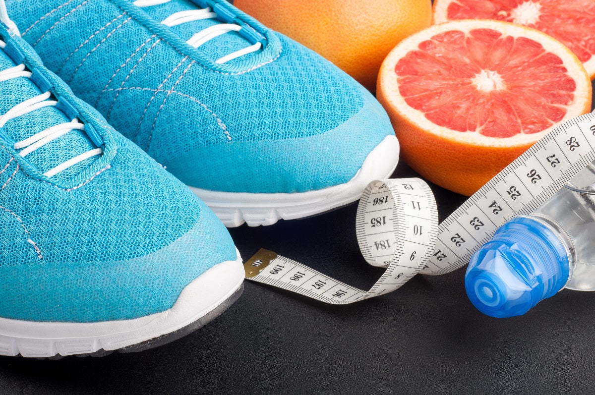 Running shoes, measuring tape, a water bottle, a whole grapefruit, and two grapefruit halves.