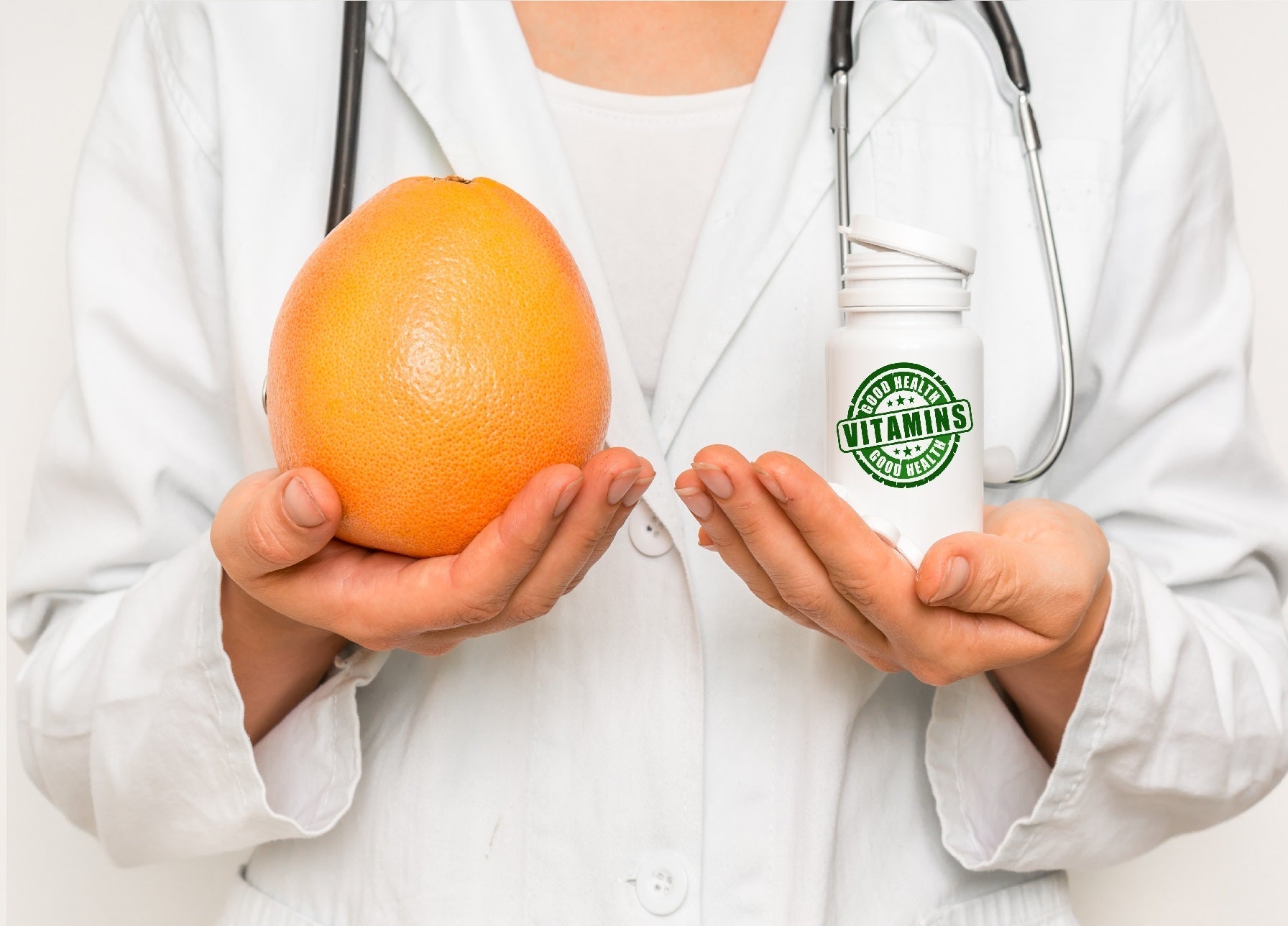 Female doctor compare pile of pills with fresh grapefruit