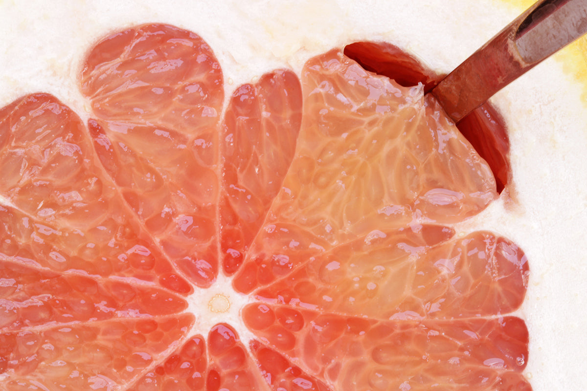 A close up shot of a grapefruit half section with a spoon in it