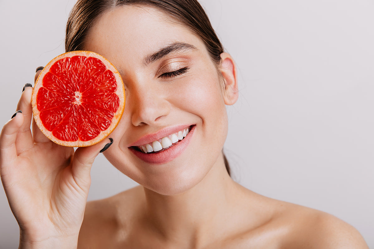 A woman with healthy skin holding a grapefruit