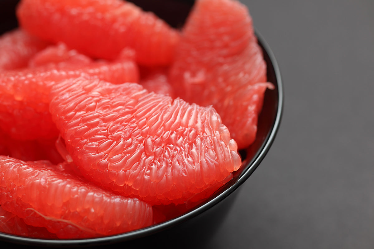 Segments of red grapefruit in a black bowl