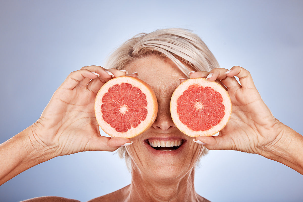 An elderly woman with grapefruit halves covering her eyes