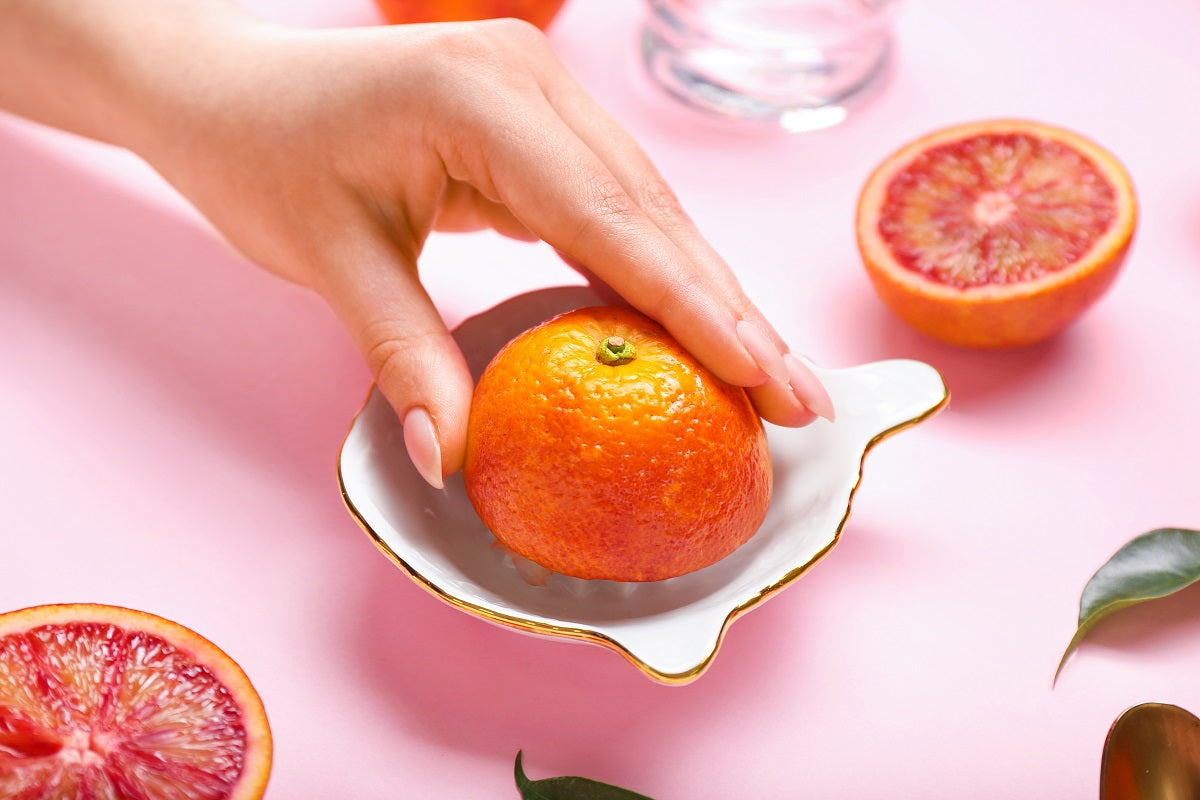 A person squeezes the juice from a grapefruit.