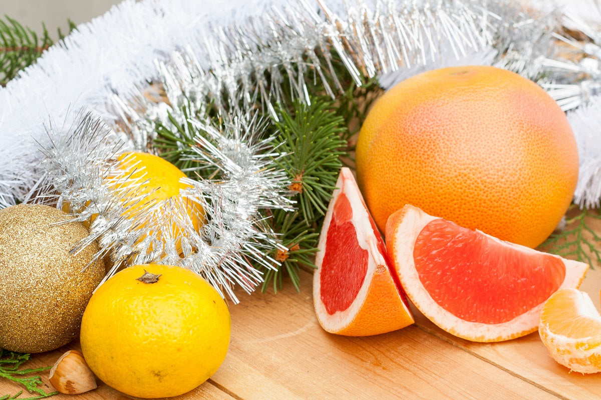 Cut grapefruit in front of Christmas tinsel.