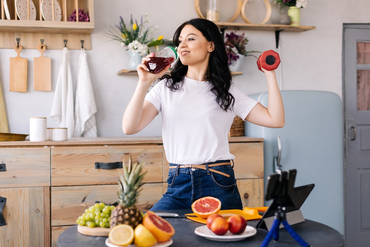 Energized woman drinks grapefruit smoothie with grapefruit and other fruits and vegetables on the table.