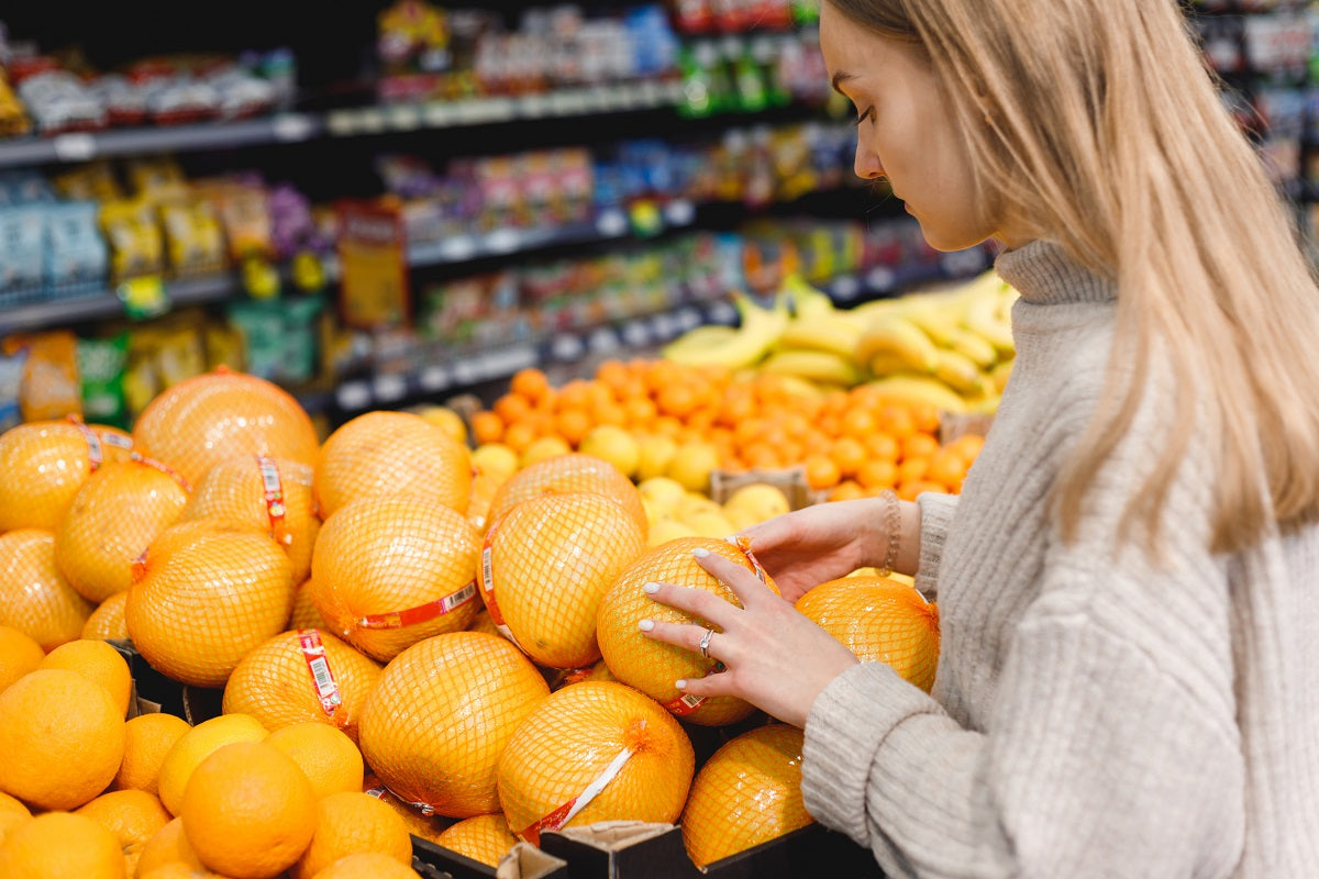 A woman looking over a Texas Rio Red grapefruit display.