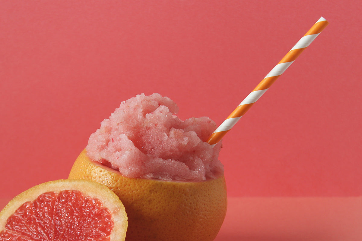 A grapefruit rind filled with grapefruit ice cream with a paper straw