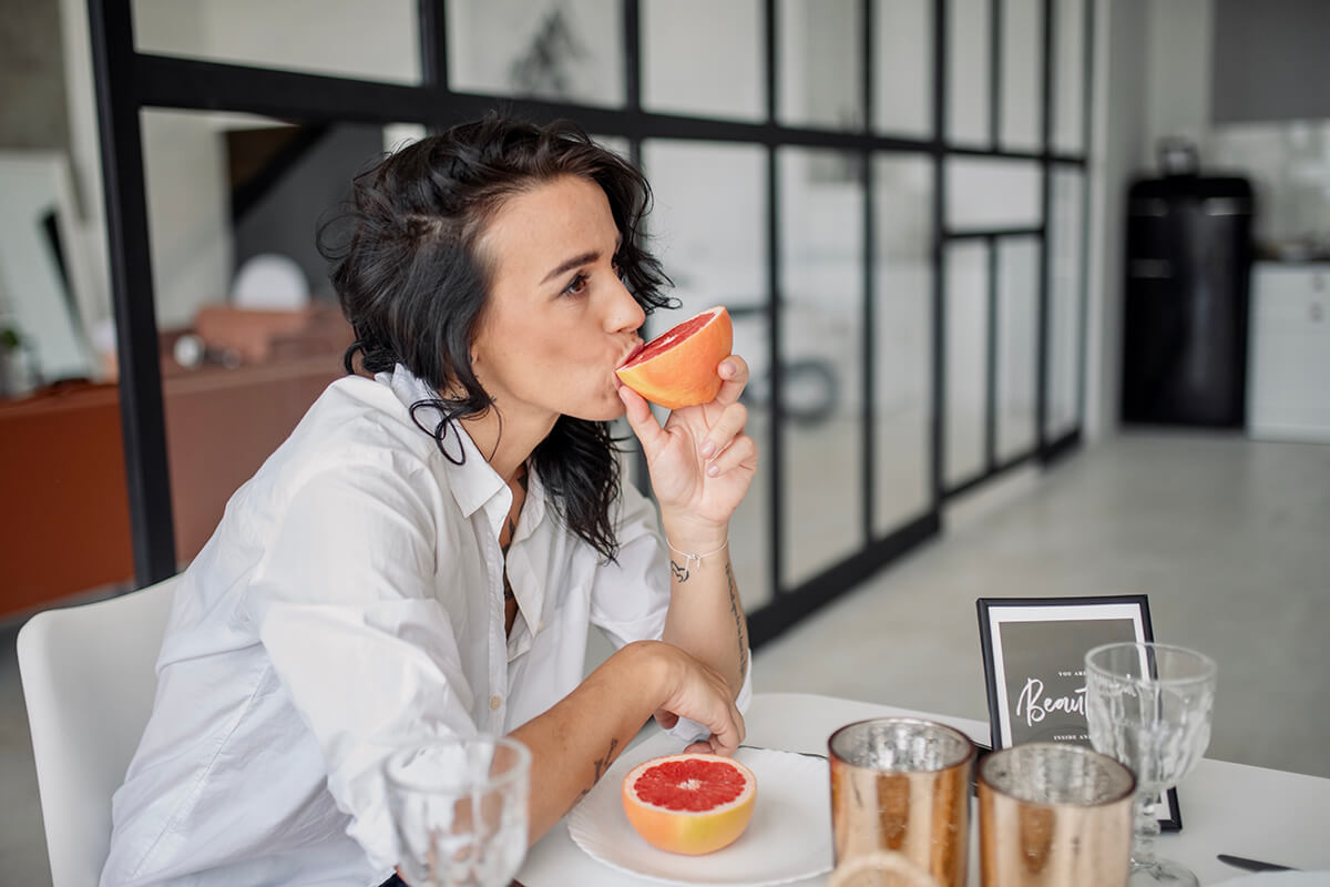 A woman eating grapefruit at the dining table